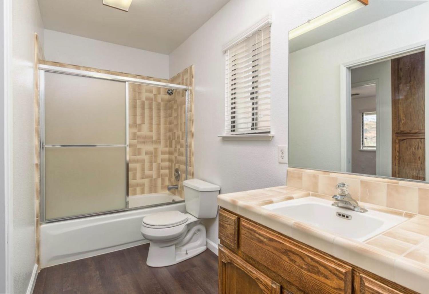 27817 Sky Harbour Road Friant, CA 93626 - Photo 17 of 36 a bathroom with a granite countertop sink toilet a mirror and shower