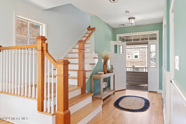 a view of an entryway with wooden floor leading to a furnished livingroom and windows