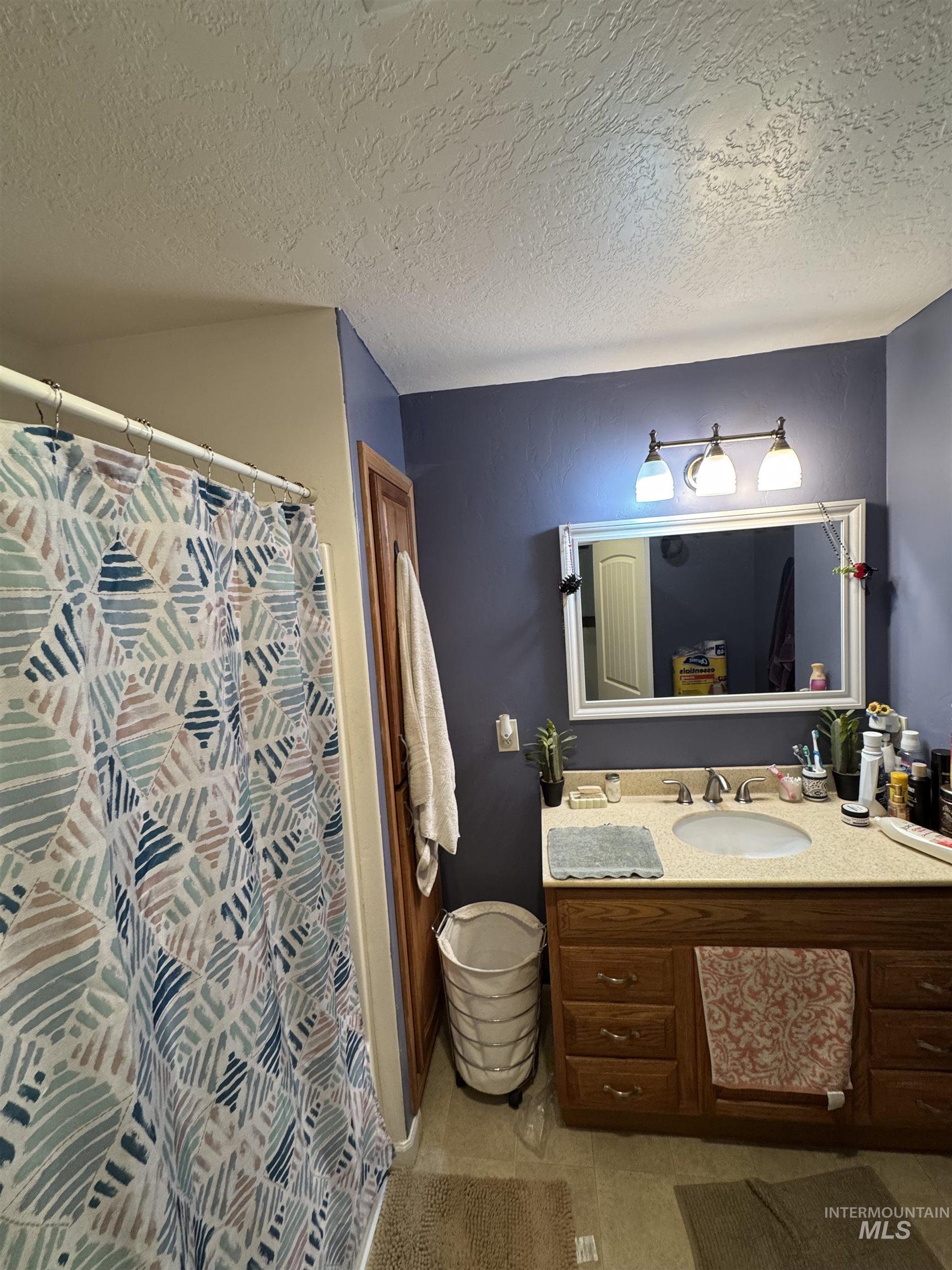 9101 South Powerline Road Nampa, ID 83686 - Photo 11 of 12 Bathroom featuring vanity, light tile patterned floors, a textured ceiling, and curtained shower