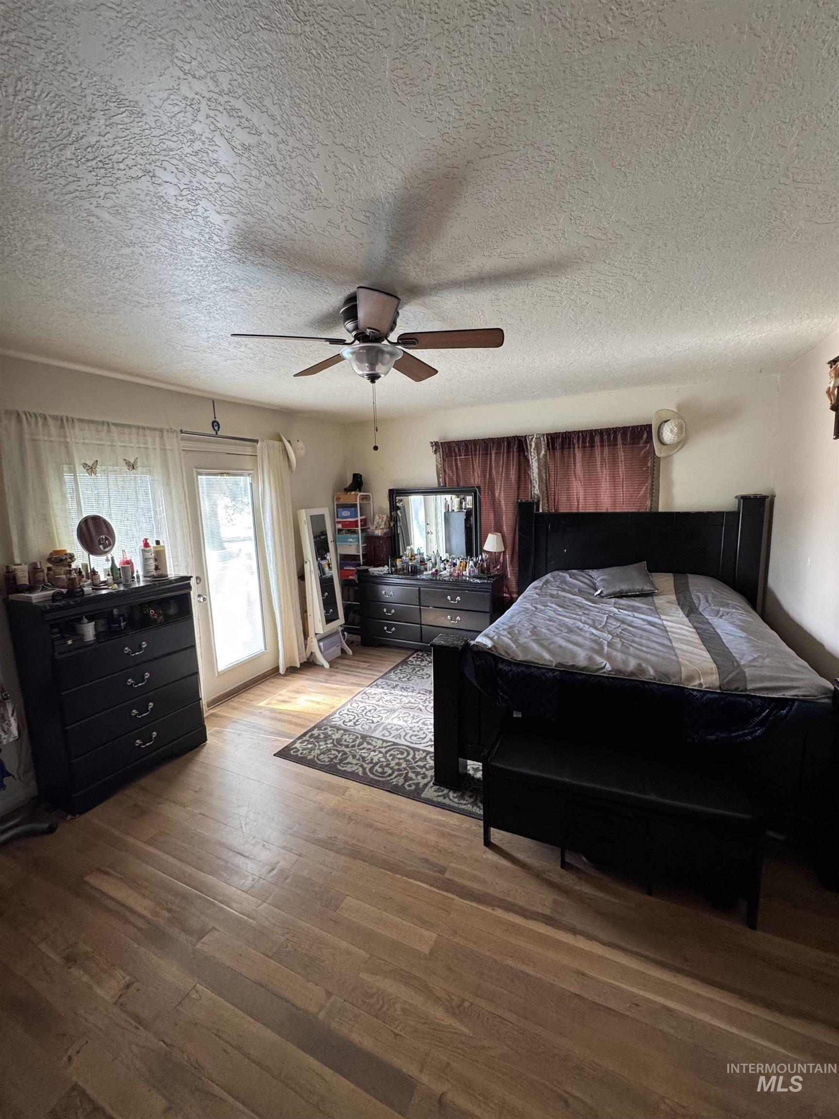 9101 South Powerline Road Nampa, ID 83686 - Photo 12 of 12 Bedroom featuring access to outside, a textured ceiling, wood finished floors, and a ceiling fan