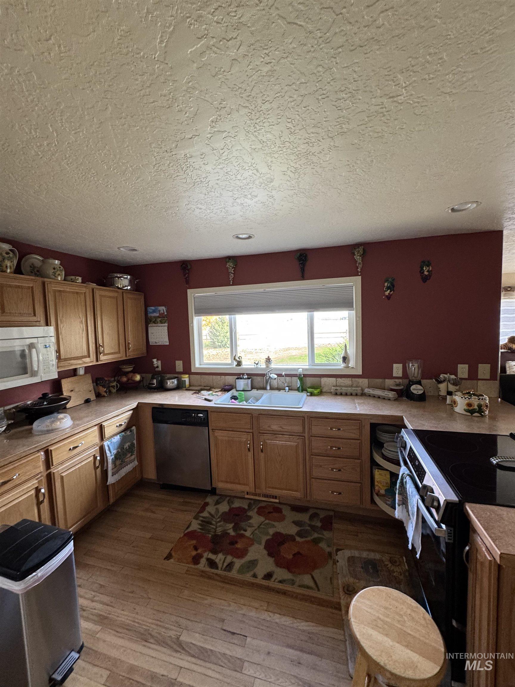 9101 South Powerline Road Nampa, ID 83686 - Photo 6 of 12 Kitchen with electric stove, brown cabinetry, light wood-type flooring, and a textured ceiling
