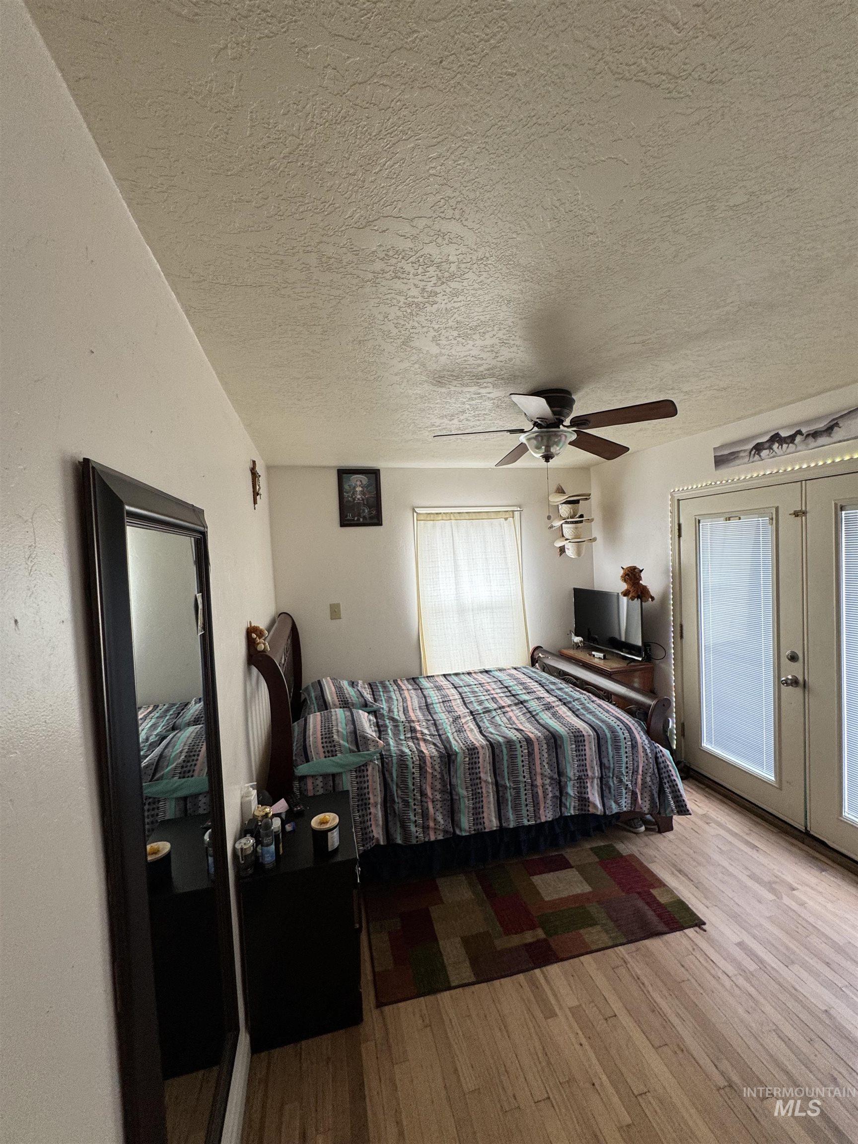 9101 South Powerline Road Nampa, ID 83686 - Photo 9 of 12 Bedroom with hardwood / wood-style flooring, a textured ceiling, ceiling fan, and french doors