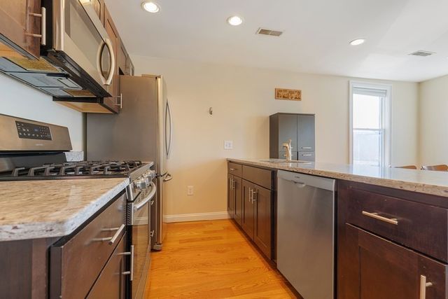 a kitchen with stainless steel appliances granite countertop a sink a stove and a refrigerator