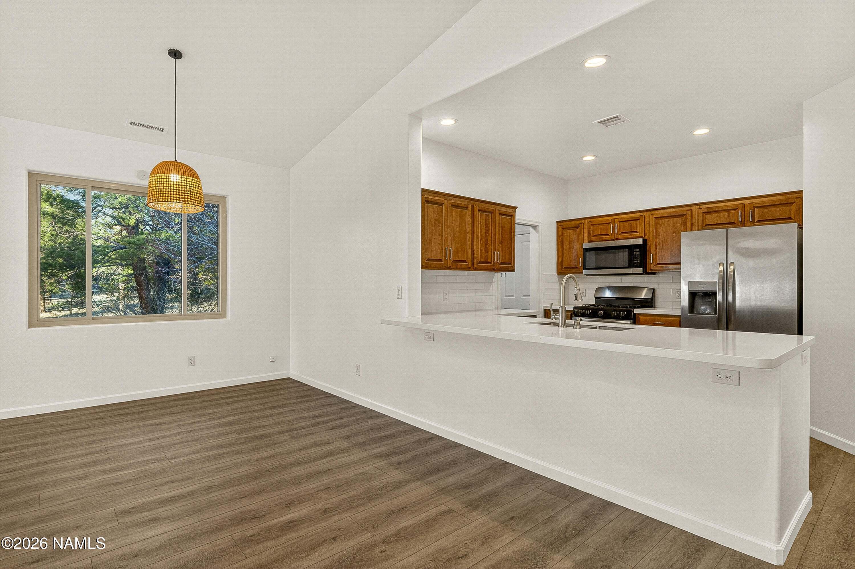 600 Brookline Loop Williams, AZ 86046 - Photo 13 of 43 a view of kitchen with stainless steel appliances granite countertop a stove a refrigerator a sink a microwave oven with a dining table and chairs with wooden floor