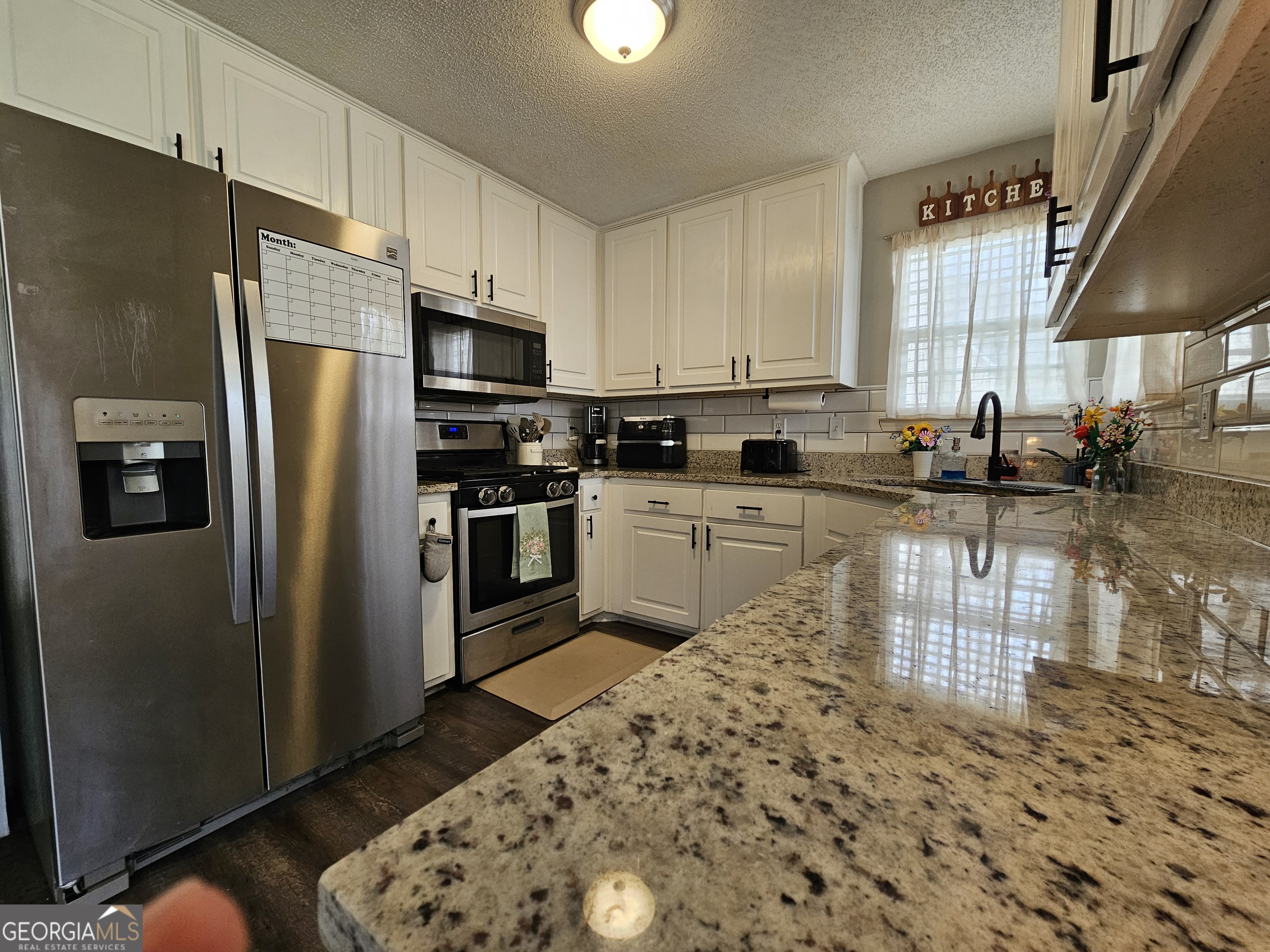 5077 Meadow Trace Fairburn, GA 30213 - Photo 29 of 43 a kitchen with stainless steel appliances granite countertop a refrigerator a stove a sink a dining table and chairs