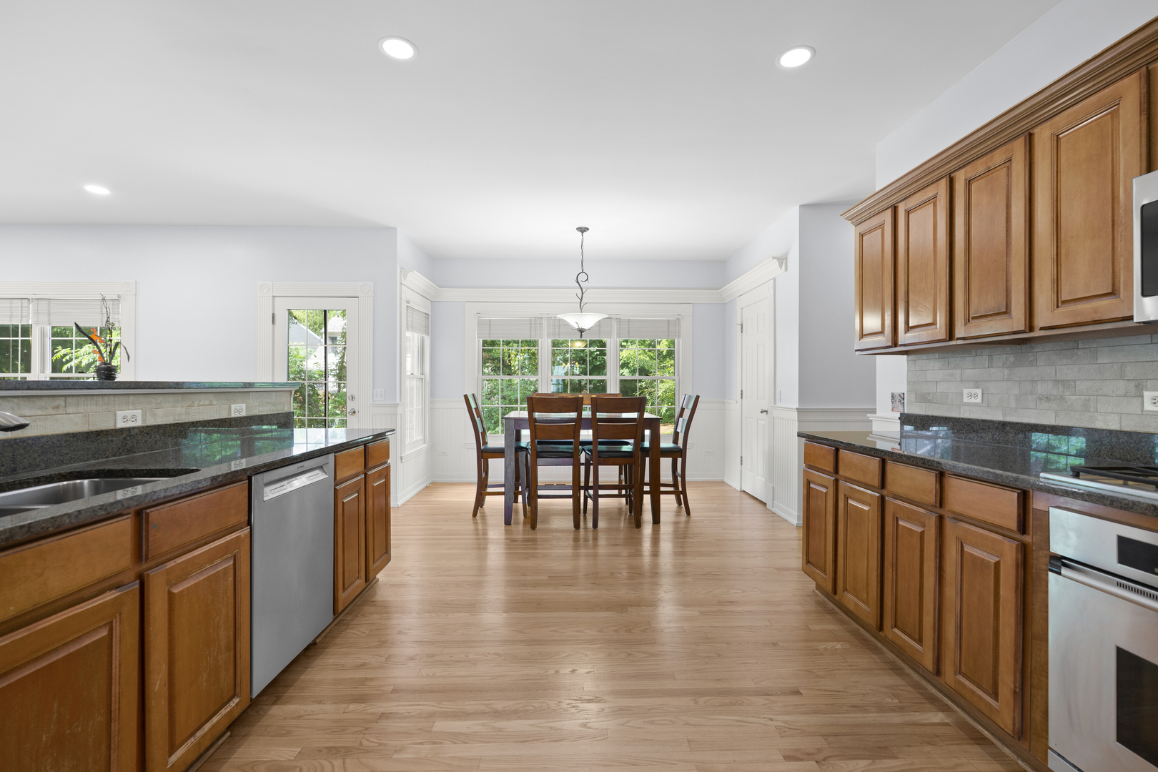 662 Waterbury Avenue Gurnee, IL 60031 - Photo 15 of 51 a kitchen with stainless steel appliances granite countertop wooden floor a dining table and chairs