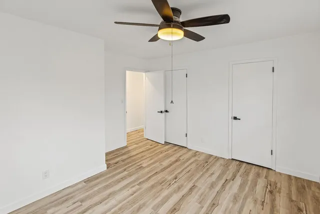 an empty room with a window and a fan