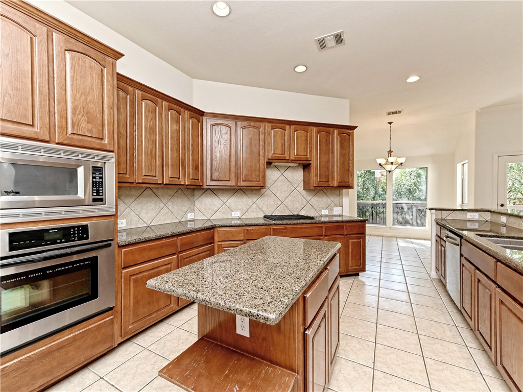 7909 Cobblestone Austin, TX 78735 - Photo 2 of 12 a kitchen with stainless steel appliances granite countertop a stove top oven a sink dishwasher and cabinets with wooden floor
