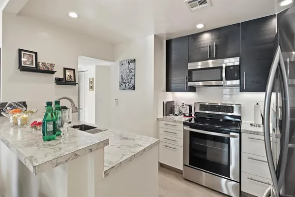 a kitchen with stainless steel appliances kitchen island granite countertop a stove refrigerator and microwave