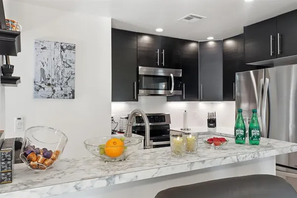 a kitchen with stainless steel appliances kitchen island granite countertop a plate of food and cabinets