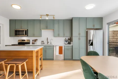 a kitchen with stainless steel appliances a stove a sink a microwave a refrigerator and chairs