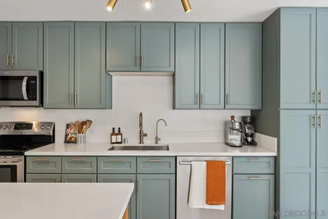 a kitchen with kitchen island a stove a sink dishwasher and white cabinets with wooden floor