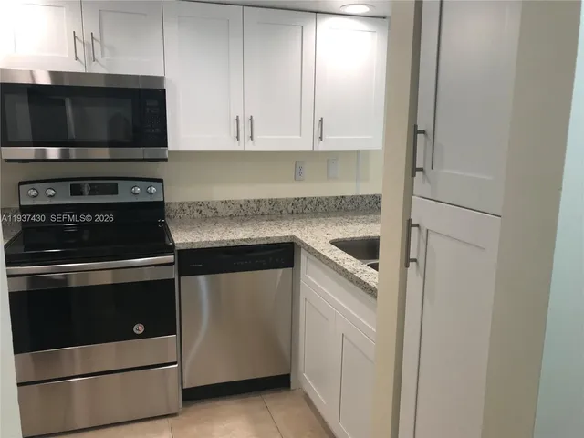 a kitchen with granite countertop white cabinets and stainless steel appliances