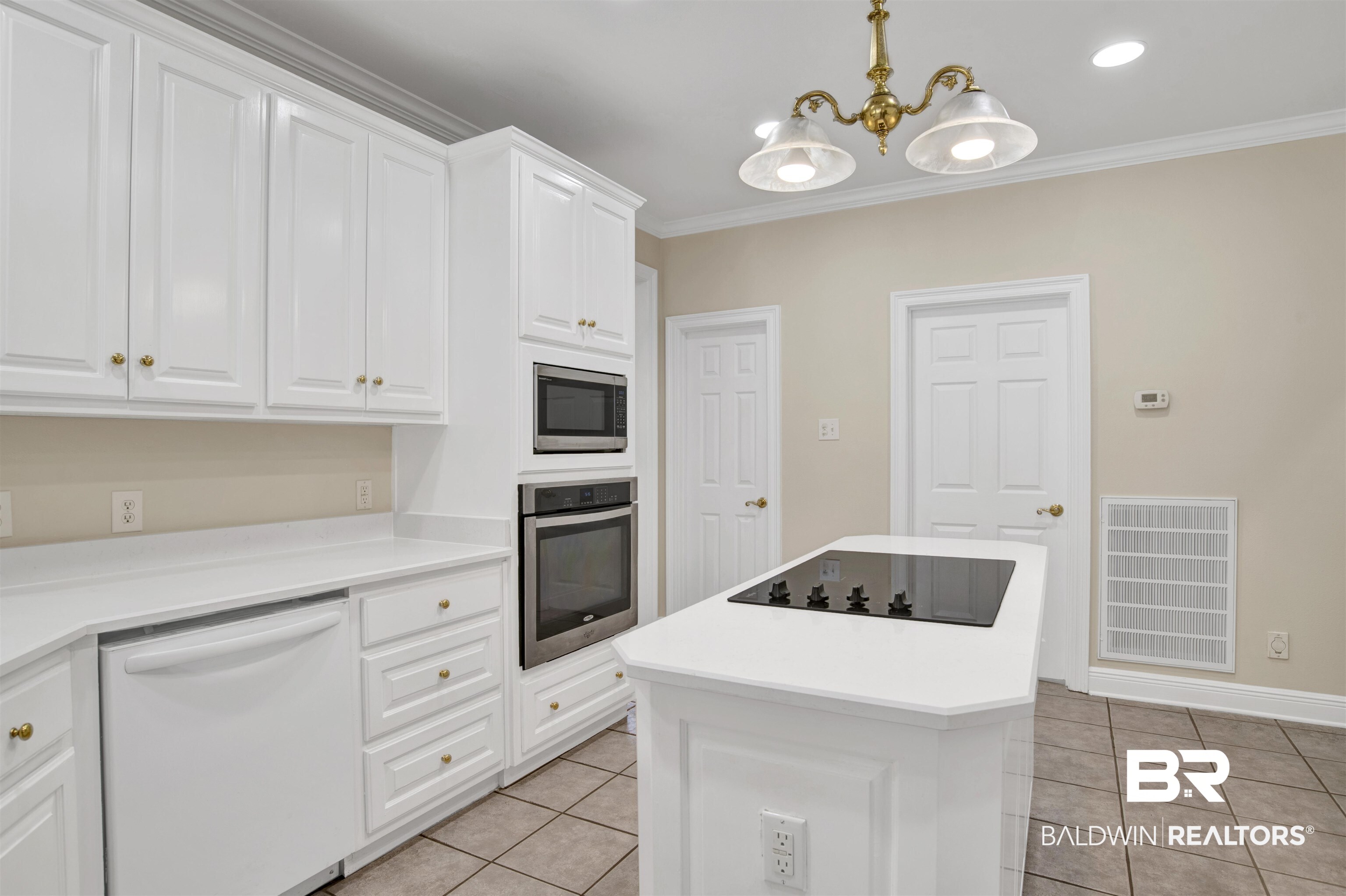 8847 Dawes Lake Road South Mobile, AL 36619 - Photo 9 of 47 Kitchen featuring white cabinetry with brass hardware, a central island with an integrated cooktop, stainless steel built-in microwave and oven, a white dishwasher, and tiled flooring