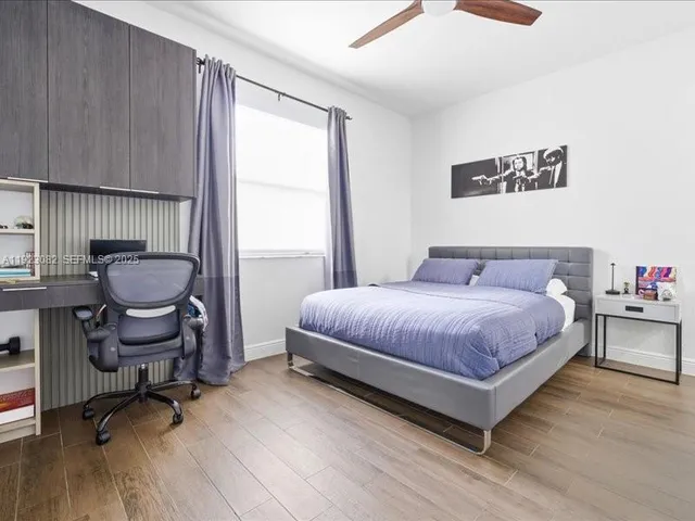 a bedroom with a bed a chair and a potted plant on dresser