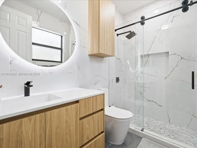 a bathroom with a granite countertop sink a toilet and shower