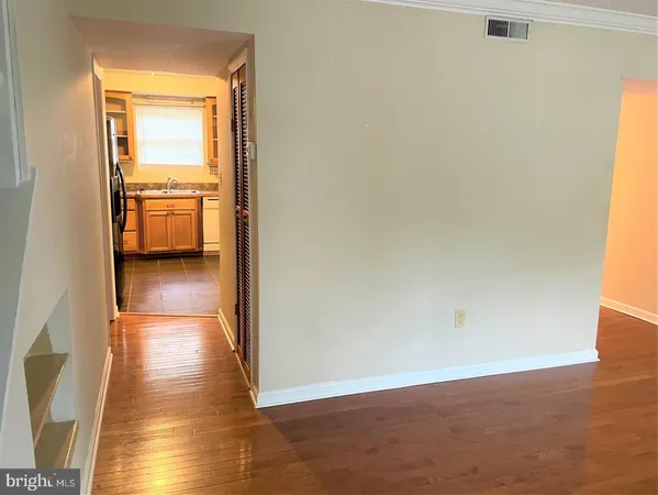 a view of a hallway with wooden floor and a room