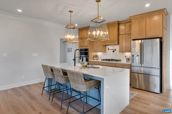 a kitchen with stainless steel appliances kitchen island granite countertop a refrigerator a stove a sink a dining table and chairs with wooden floor