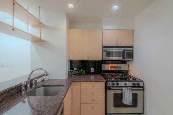 a kitchen with stainless steel appliances granite countertop a sink a stove and a refrigerator