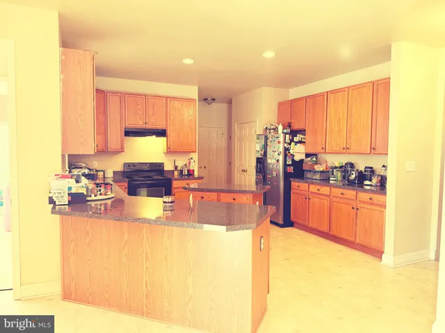 a large kitchen with kitchen island a sink a stove and a refrigerator