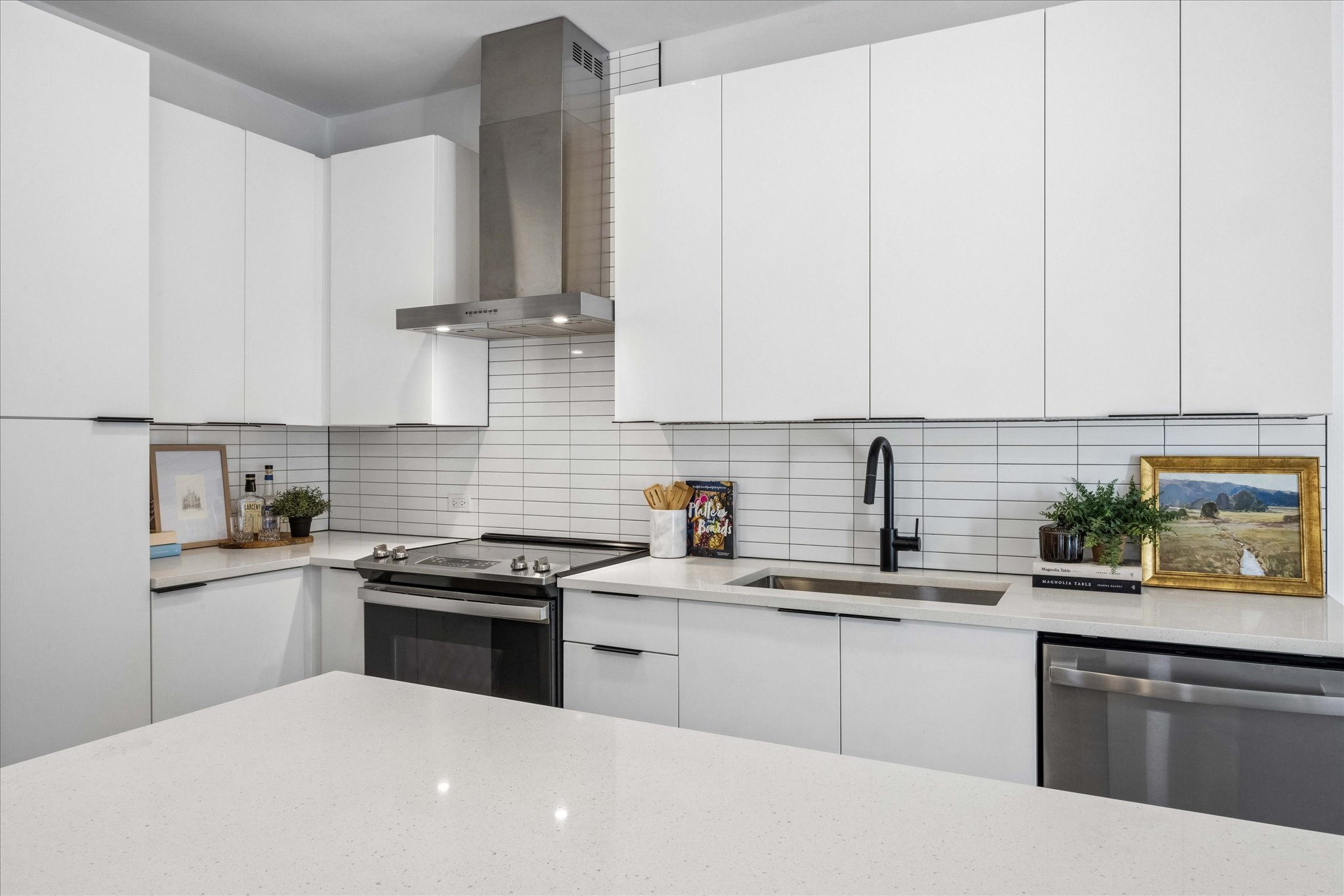 2220 Webberville Road, Unit 216 Austin, TX 78702 - Photo 1 of 26 Modern kitchen featuring abundant white cabinetry, stainless steel appliances, a subway tile backsplash, a matte black faucet, and light-toned countertops