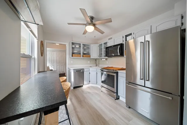 a living room with stainless steel appliances wooden floor and a window