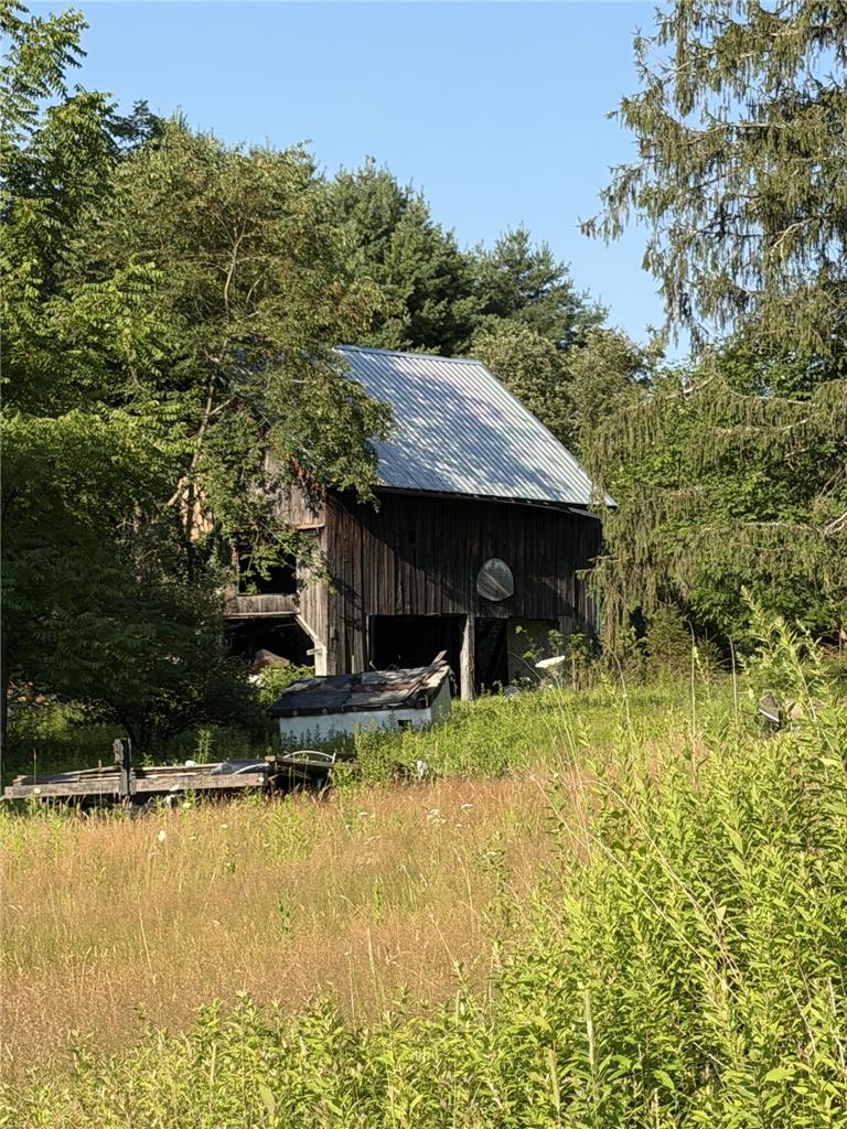 730 Ridge Road Shickshinny, PA 18655 - Photo 16 of 44 A classic barn, surrounded by mature trees, awaits restoration amidst a peaceful, verdant landscape.