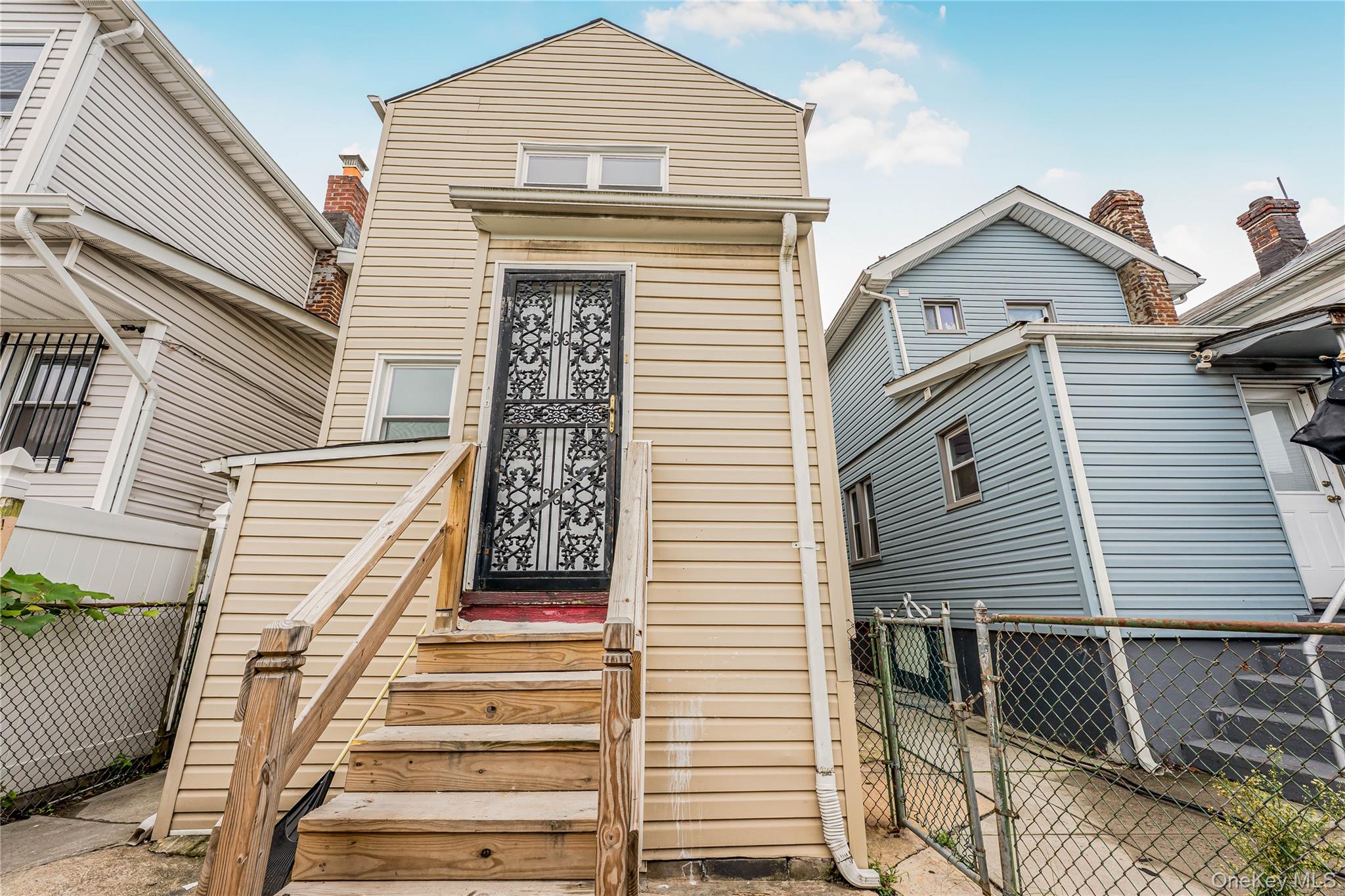 173-43 103rd Road Queens, NY 11433 - Photo 38 of 43 Vertical siding exterior with wood stairs leading to an entrance