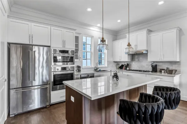 a kitchen with a refrigerator a sink and a stove top oven with wooden floor