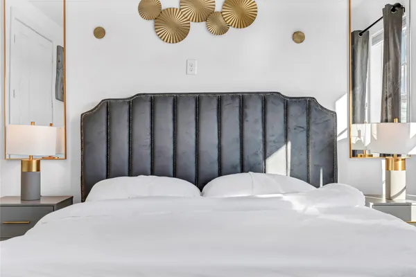 a large white bed in a bedroom next to a window