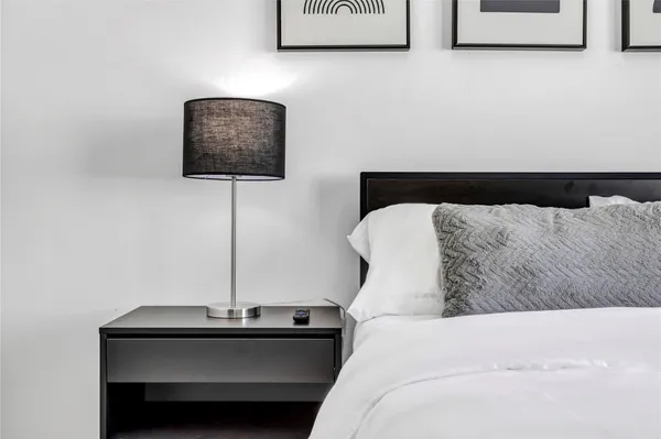 a bedroom with a bed and a lamp on dresser