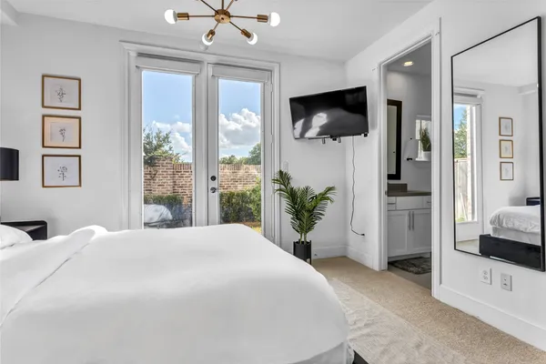 a bedroom with a bed flat screen tv and a chandelier