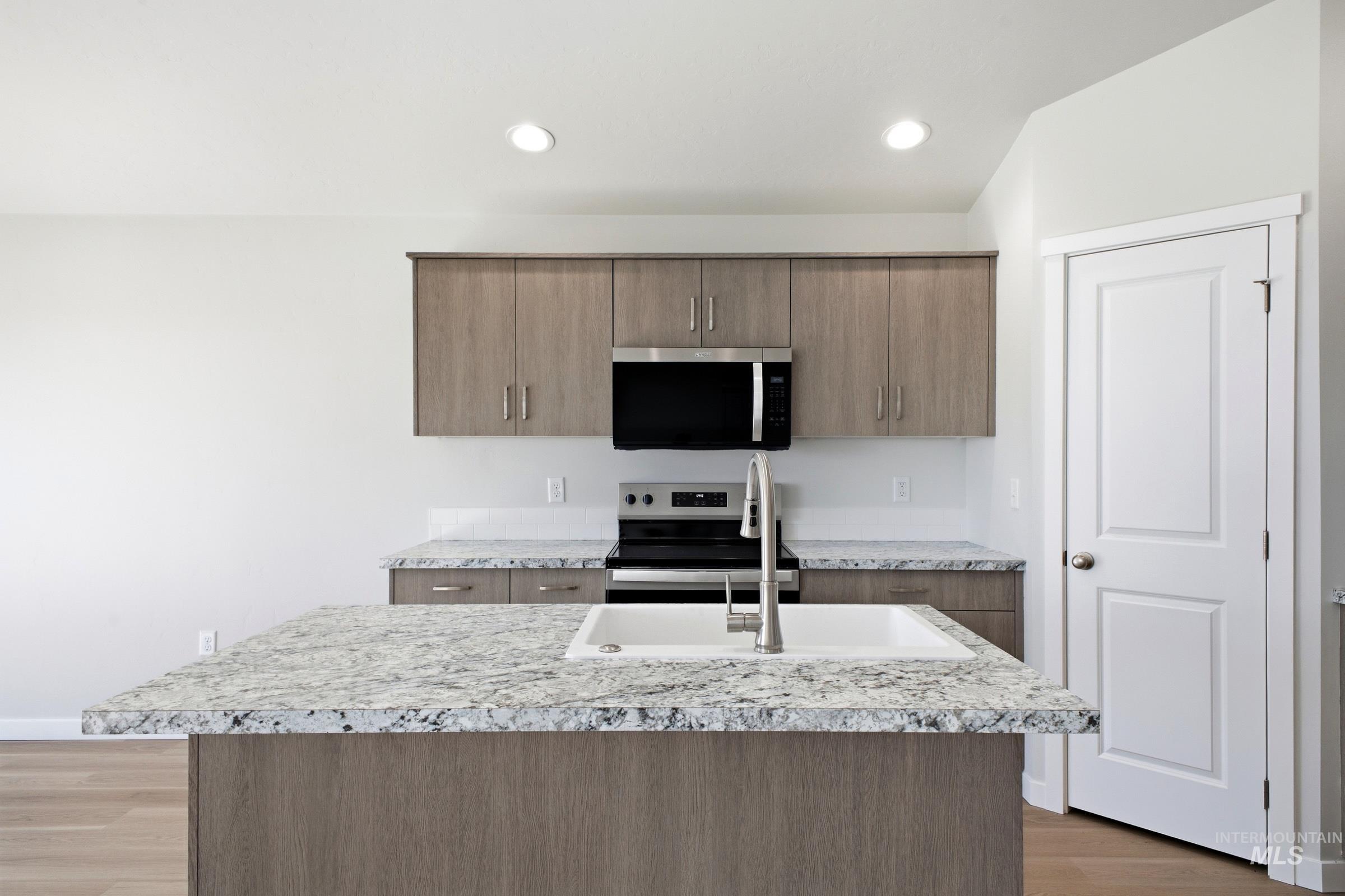 16434 Backfill Avenue Caldwell, ID 83607 - Photo 3 of 19 Kitchen featuring an island with an integrated sink, granite countertops, wood-finish cabinetry, and stainless steel appliances