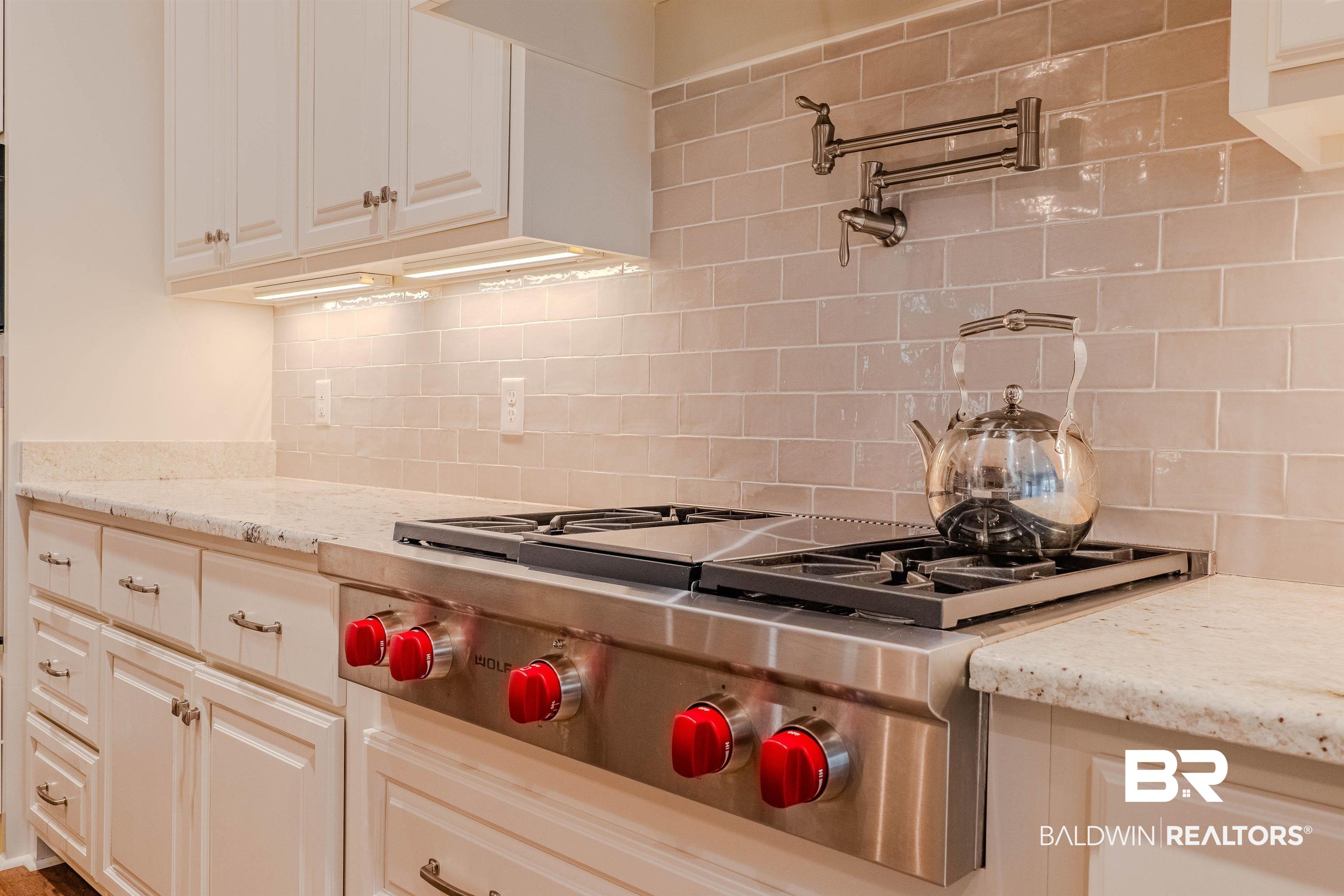 708 Manning Place Fairhope, AL 36532 - Photo 11 of 58 Kitchen featuring light stone countertops, stainless steel gas cooktop, and decorative backsplash