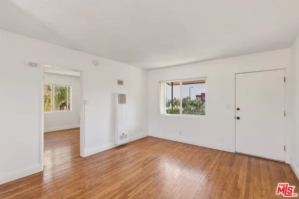 a view of an empty room with wooden floor and a window
