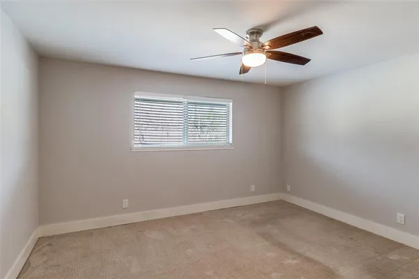 an empty room with ceiling fan and window