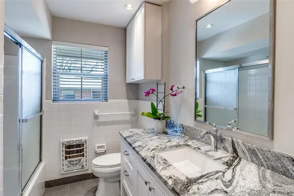 a bathroom with a granite countertop toilet a sink and a mirror