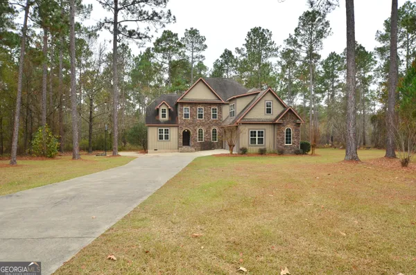 a front view of a house with a yard and trees
