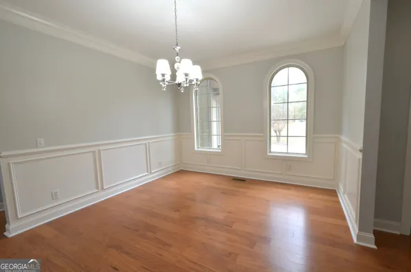 an empty room with chandelier fan and windows