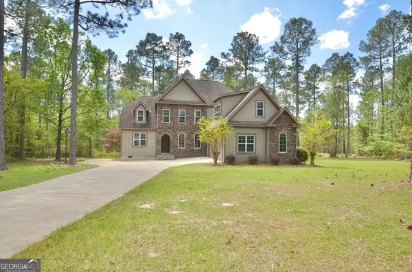 a front view of a house with a garden and trees
