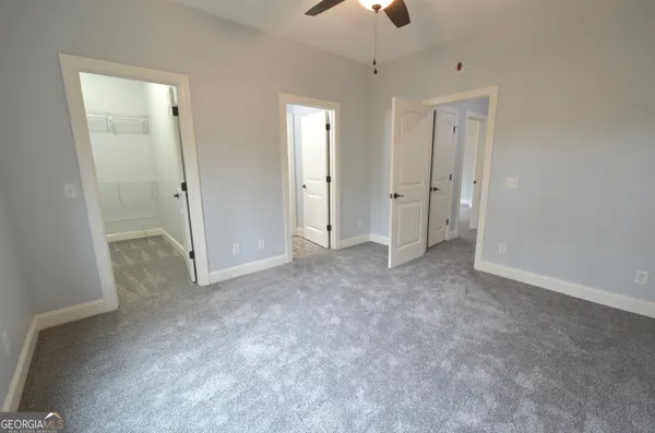 an empty room with chandelier fan and windows
