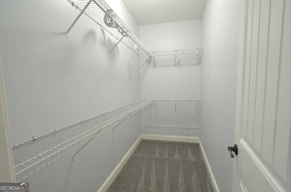 a view of an empty room and chandelier fan