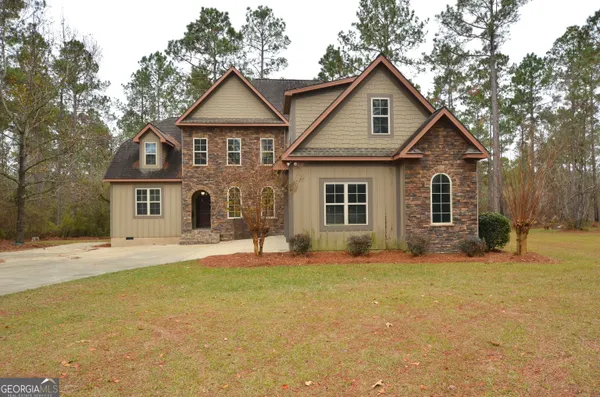 a front view of a house with a yard and trees