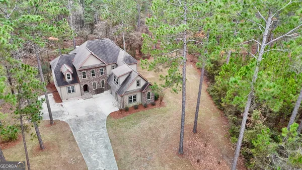 an aerial view of residential house with outdoor space and trees all around