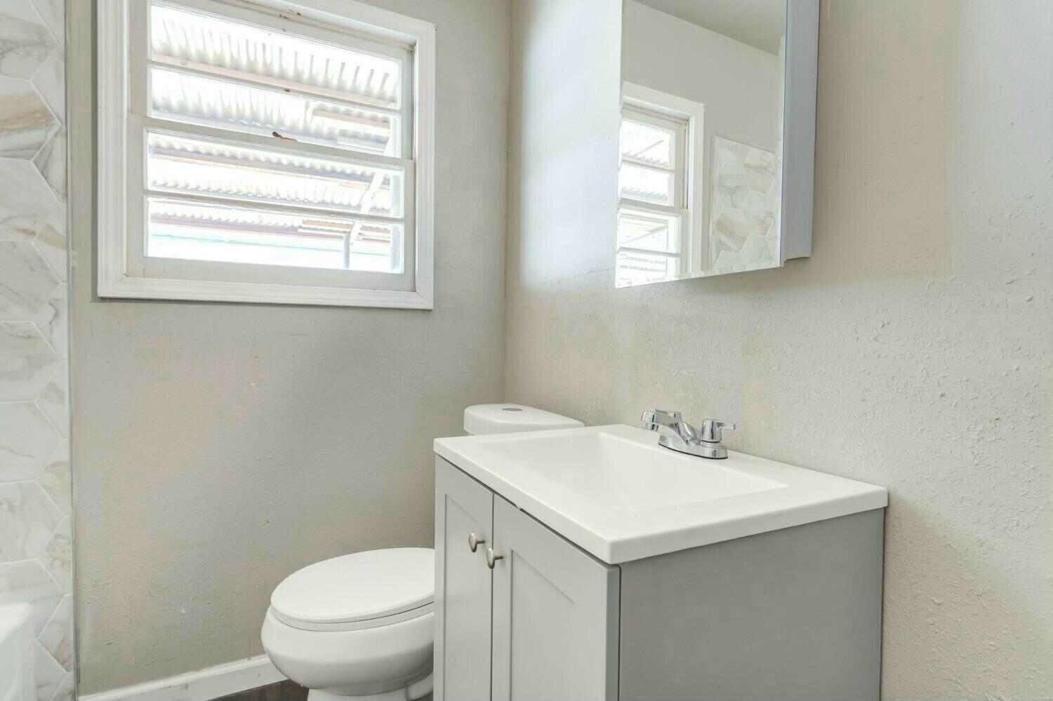 4407 49th Street Lubbock, TX 79414 - Photo 21 of 23 a bathroom with a sink a toilet and a window