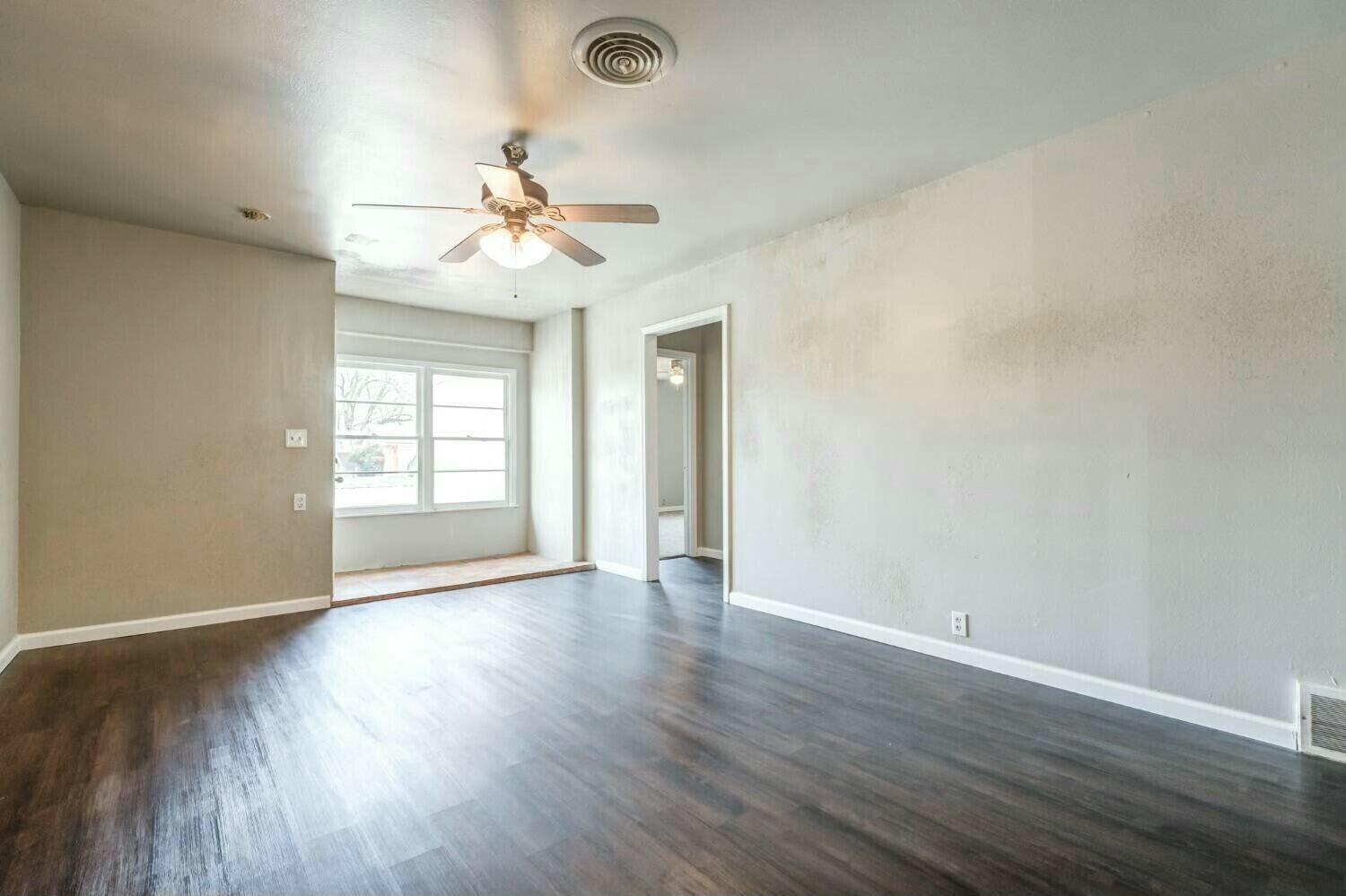 4407 49th Street Lubbock, TX 79414 - Photo 6 of 23 an empty room with wooden floor ceiling fan and windows