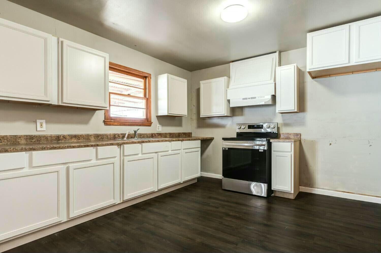 4407 49th Street Lubbock, TX 79414 - Photo 9 of 23 a kitchen with granite countertop white cabinets and a wooden floor
