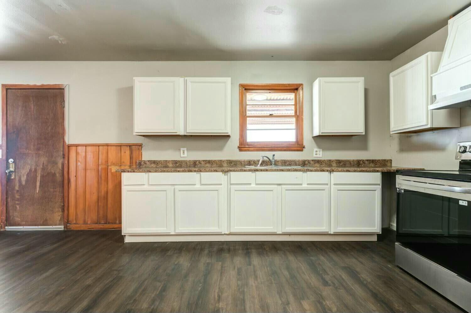4407 49th Street Lubbock, TX 79414 - Photo 10 of 23 a kitchen with granite countertop wooden floors a sink and a stove