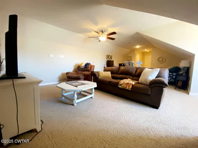 a living room with furniture a ceiling fan a lamp and a window