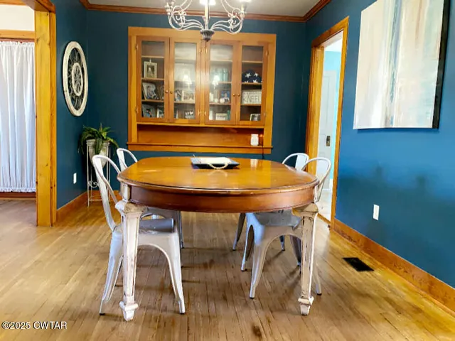 a view of a dining room with furniture a chandelier and wooden floor